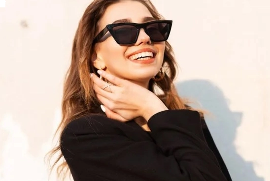 Mulher com cabelo castanho usando óculos de sol gatinho com lente e armação pretas