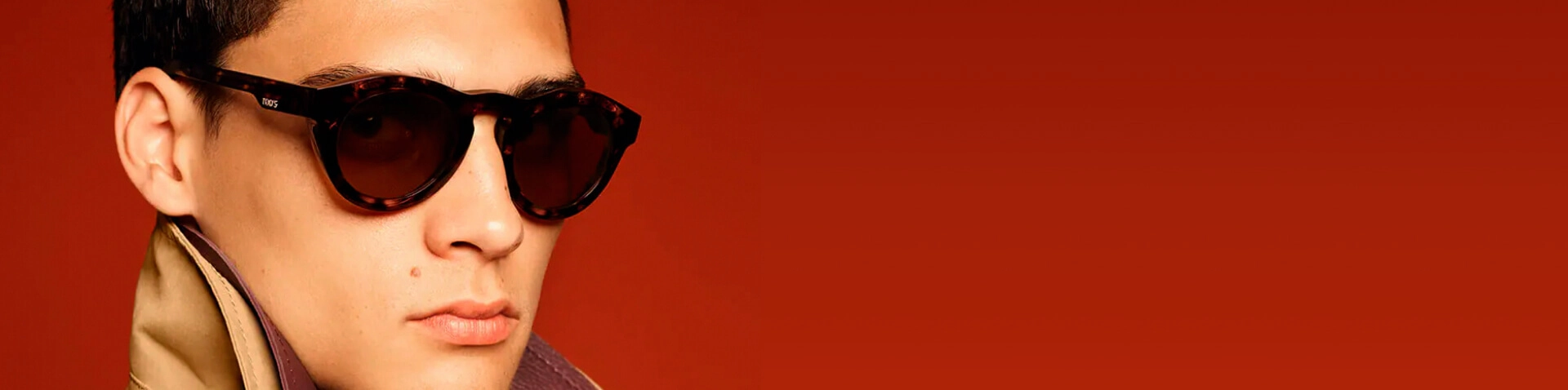 Banner homem com cabelos castanhos usando óculos de sol com a lente e armação marrons