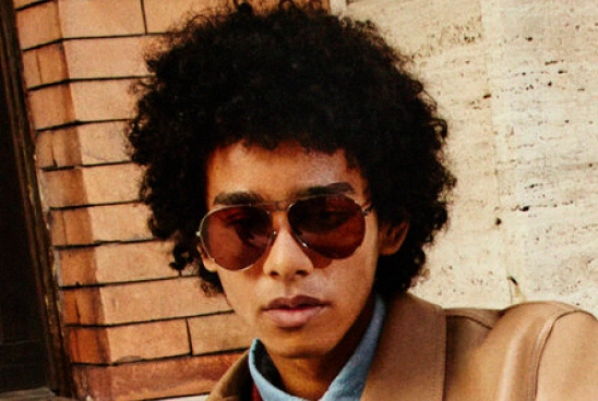 Homem com cabelos castanhos usando óculos de sol preto com armação preta