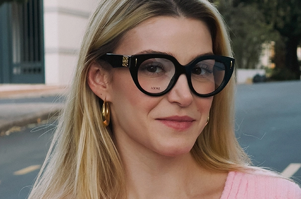 Mulher loira sorrindo com óculos de grau da marca Loewe com armação gatinho